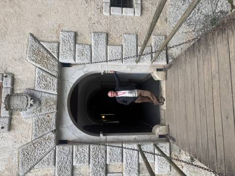       Person standing under an archway at a historic building.
  