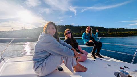       Three people posing on a boat with scenic water view.
  
