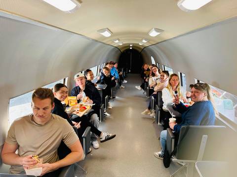      People sitting inside a converted airplane restaurant.
  