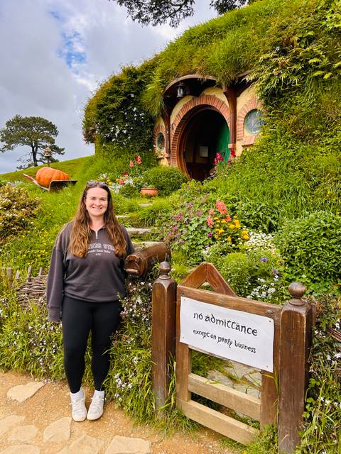       Woman posing in front of a hobbit house.
  
