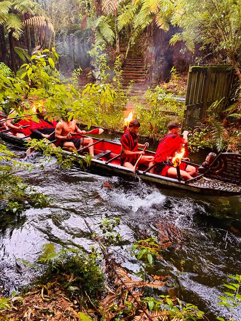       Maori canoe with warriors paddling on a river.
  