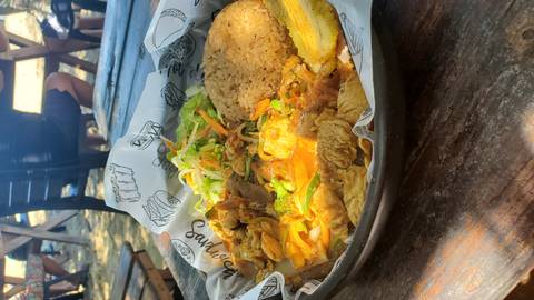       A dish of rice, vegetables, and plantains served on a wooden table.
  