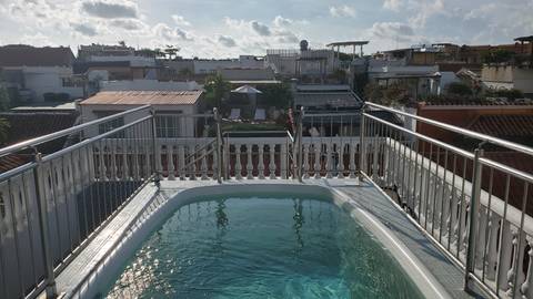 Rooftop pool overlooking a cityscape with cloudy sky.