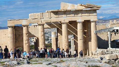       Historical columns with a view of a cityscape in the background, many tourists present.
  