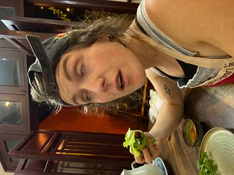 Person eating in a restaurant with an expressive face, holding food.