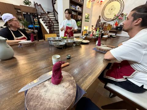 People wearing aprons around a kitchen table with cooking utensils.