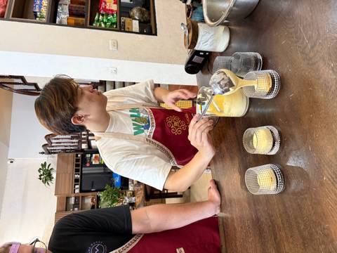 Person pouring a yellow liquid into glasses on a table.