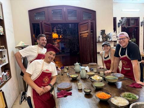 Four people smiling and standing around a table indoors.