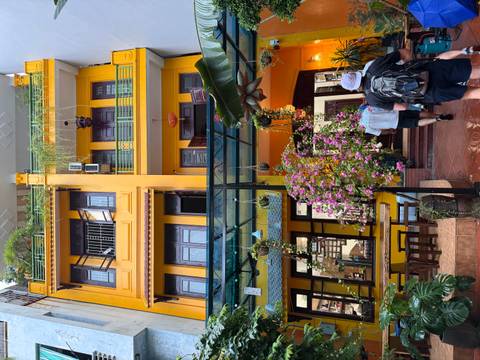 Vibrantly painted yellow building with plants and hanging decor.