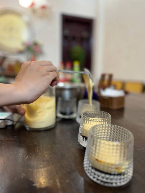Close-up of someone pouring a yellow mixture into glasses.