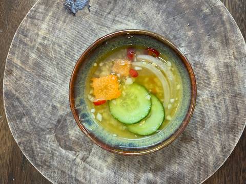 Bowl with a cucumber salad on a wooden surface.