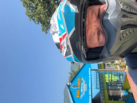 Selfie of a person wearing a helmet with a shop in the background.