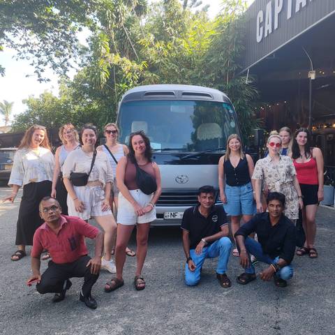 Group of people posing in front of a van.