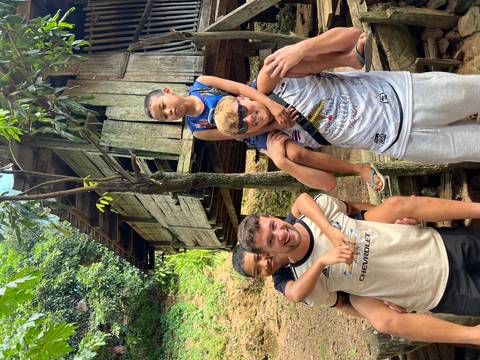       Two people with children in front of a rustic wooden house.
  
