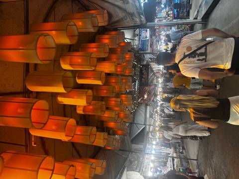       Indoor market with hanging lanterns and people walking.
  