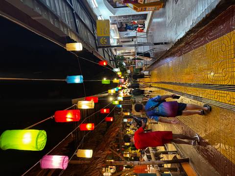       People walking under colorful lanterns at night.
  