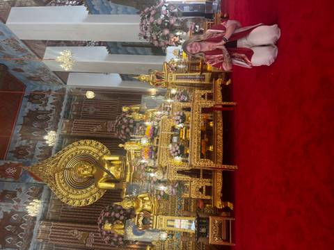       Person posing in front of a golden Buddha statue.
  