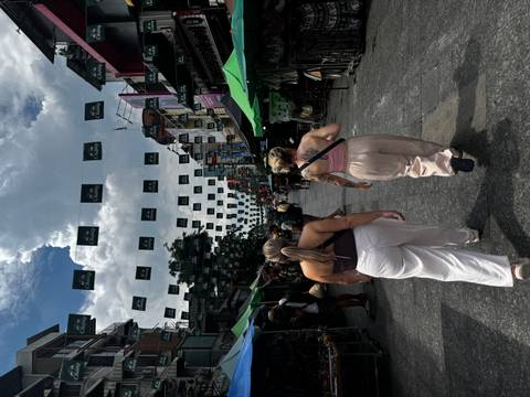       Two women walking in a busy street market.
  
