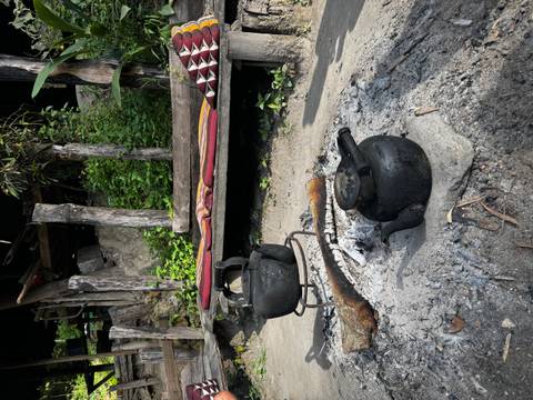       Iron kettles on fire near a rustic seating area.
  