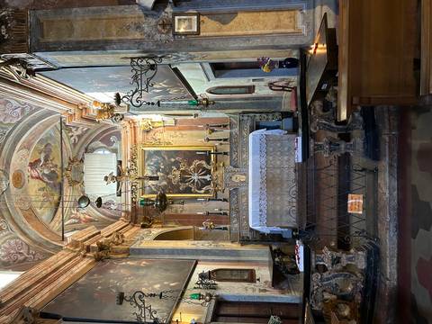 Ornate interior of an old church with paintings and altar.