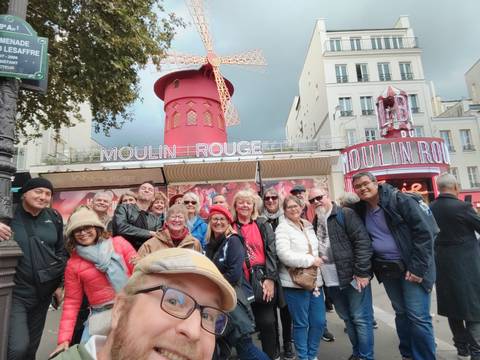 Group photo of tourists in front of the Moulin Rouge.