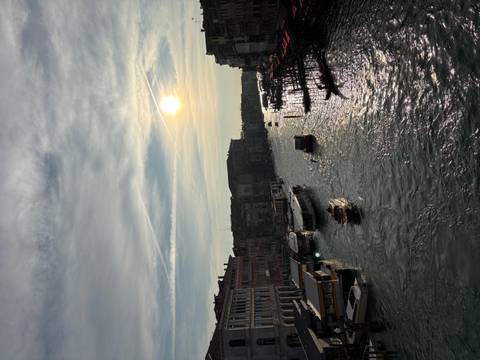 Venetian canal at sunset with boats and buildings reflected in the water.
