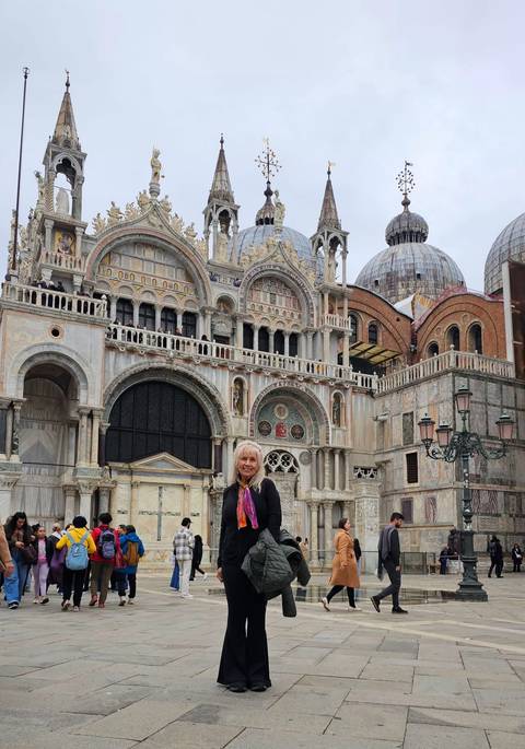 Woman posing in front of a grand basilica with domes.