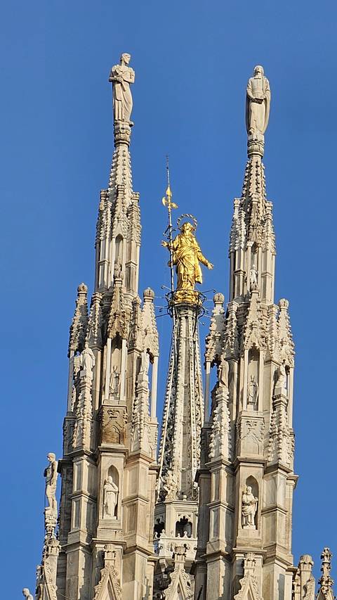 Golden statue on top of a detailed cathedral spire.