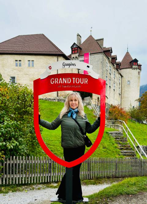 Woman posing with 'Grand Tour of Switzerland' sign.