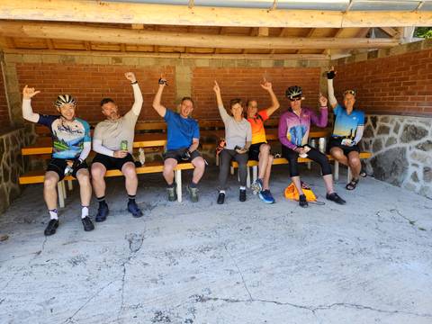 Group of cyclists sitting on benches celebrating.