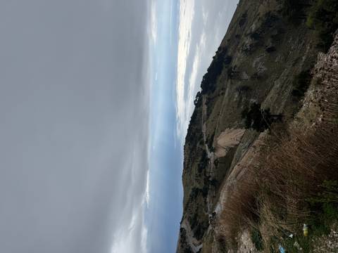 Hilly landscape with overcast sky and distant sea.