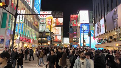 Bustling city street at night with illuminated signs and crowds.