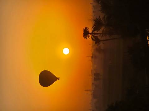 Hot air balloon floating over a sunset scene in Egypt.