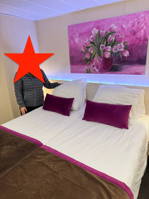 Hotel room with person standing beside a bed.