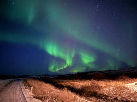 Aurora borealis over a rural landscape at night.