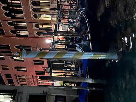 Blurred view of gondolas and buildings along a canal at night.