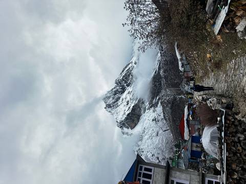       Person walking along a path towards snowy mountain peaks.
  