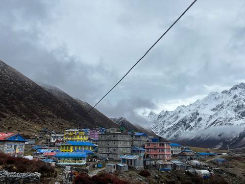       Colorful buildings in a mountainous village with snowy peaks in the background.
  