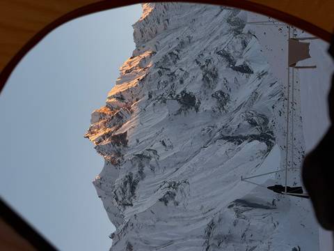       Mountainous landscape viewed from a tent.
  