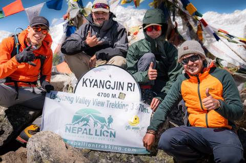       Group of climbers with a sign on Kyangjin Ri.
  