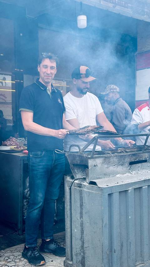       People grilling meat on a barbecue.
  