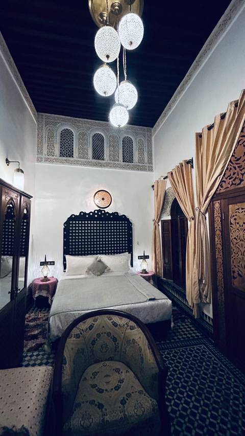       Intricately decorated room interior with a bed and drapes.
  