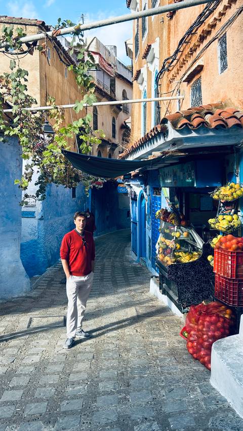       Man standing in a blue-painted street in Chefchaouen.
  