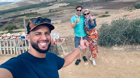       Selfie with a group of three people smiling outdoors.
  