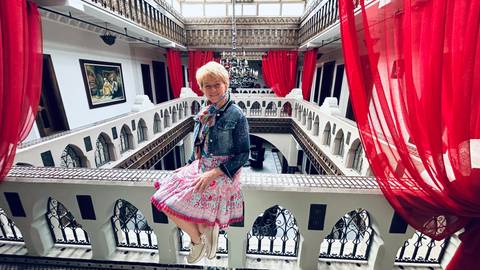       Woman sitting on a balcony in a traditional interior.
  