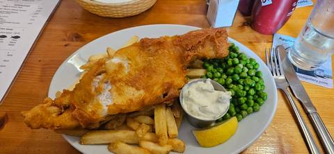       Plate of fish and chips with peas and tartar sauce.
  