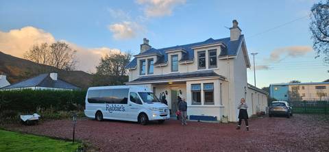       House with a Rabies tour van and two people outside.
  