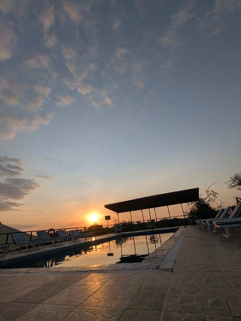 A tilted sunset over savannah lands with a building silhouette.