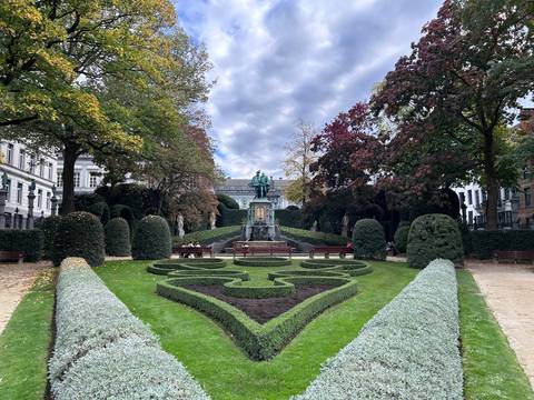 A beautifully landscaped garden with a statue and topiary hedges.
