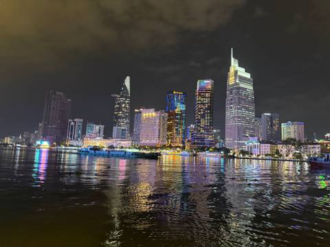       City skyline at night with illuminated buildings and reflections on water.
  